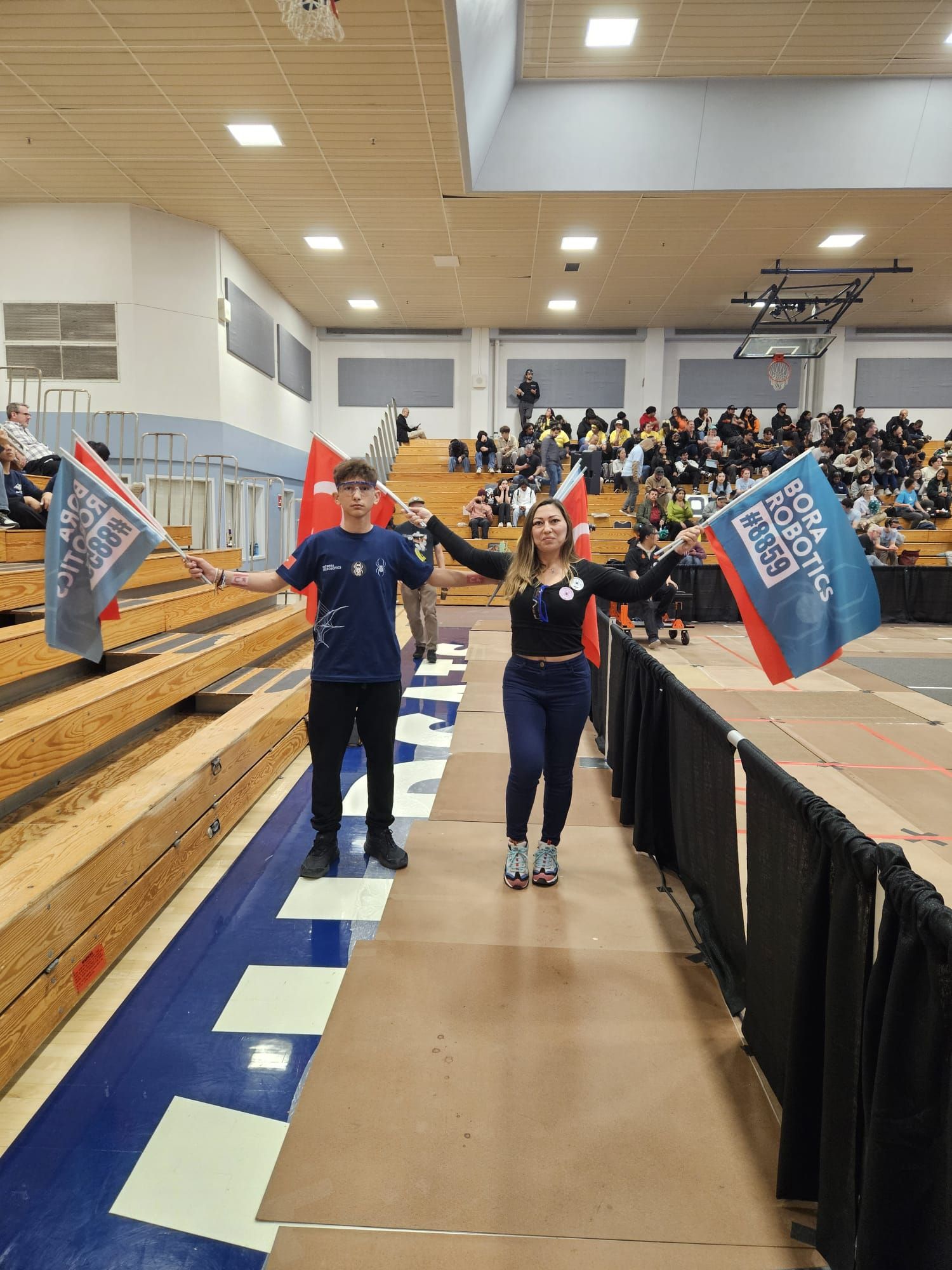 Team 9174 ve Bora Robotics üyeleri Türkiye ve KKTC bayraklarıyla salonda